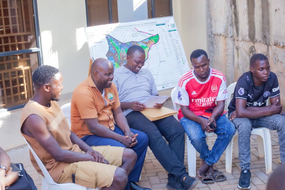 Committee members in discussion beside a map of Mukono Municipality